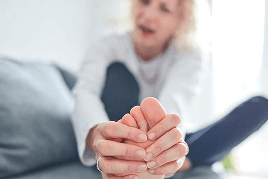 Person holding foot due to toe pain